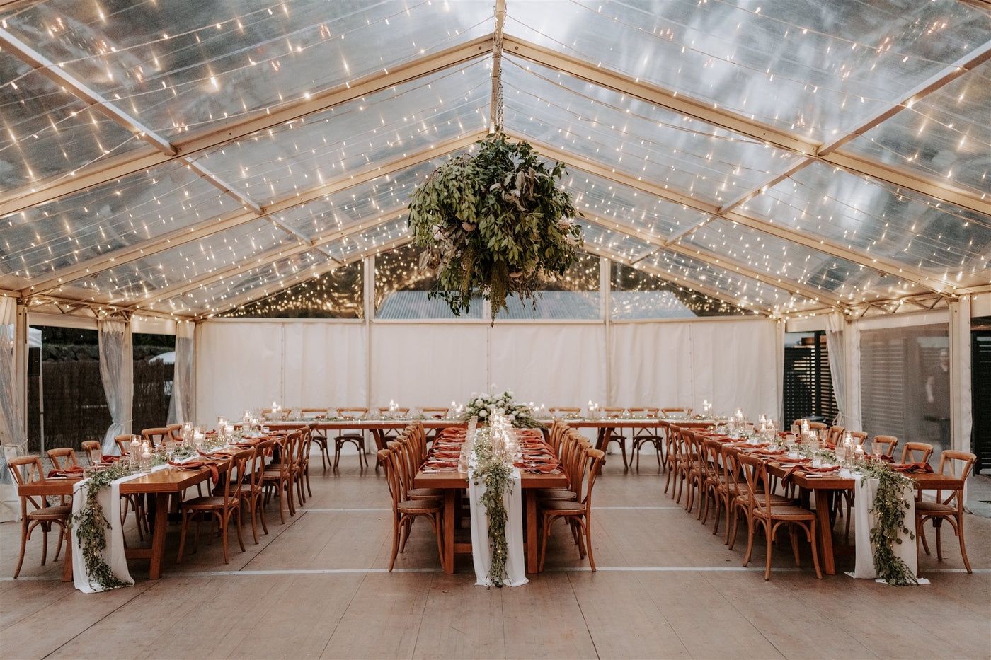 Wedding venue with tables and chairs set up in a clear marquee venue with magical lights.